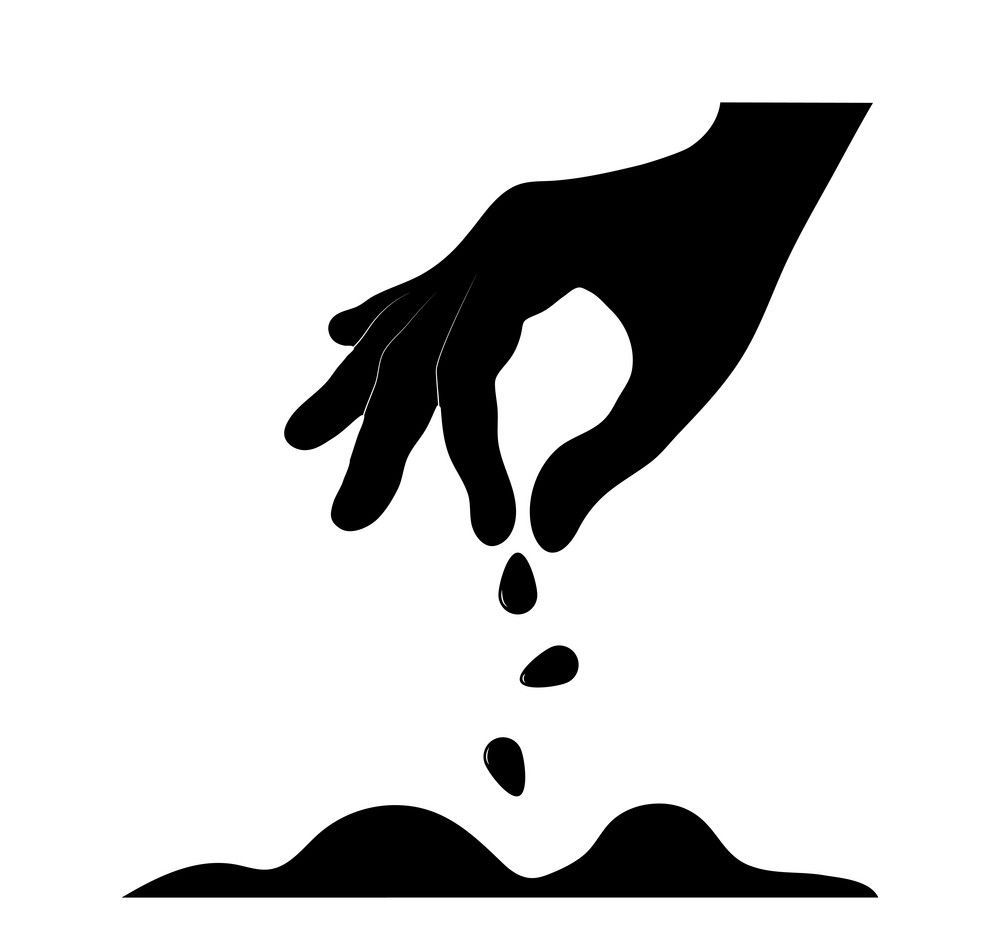 A hand is sprinkling seeds into the ground.