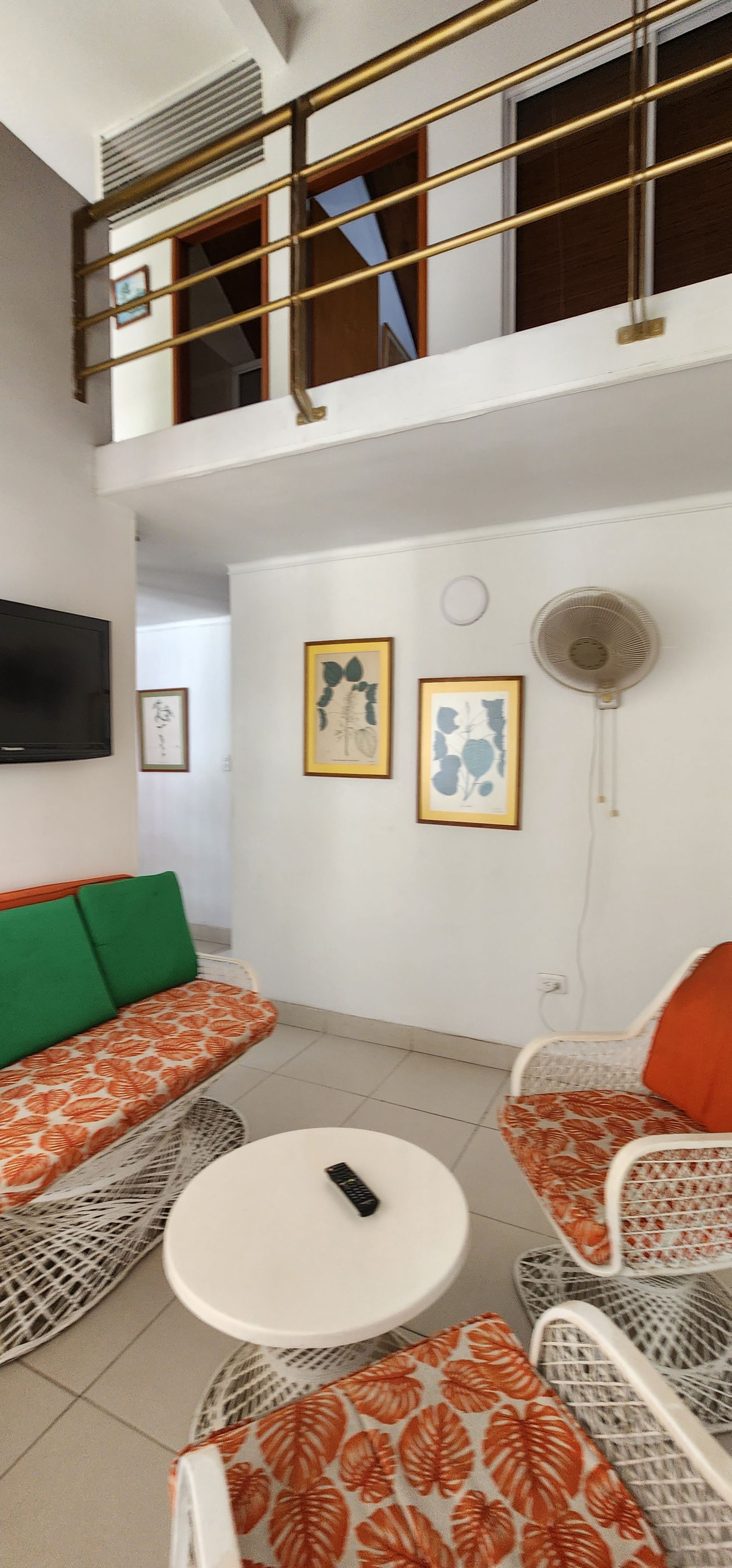 Una acogedora sala de estar con asientos estampados en naranja y verde, una mesa de centro redonda blanca y un altillo de madera.