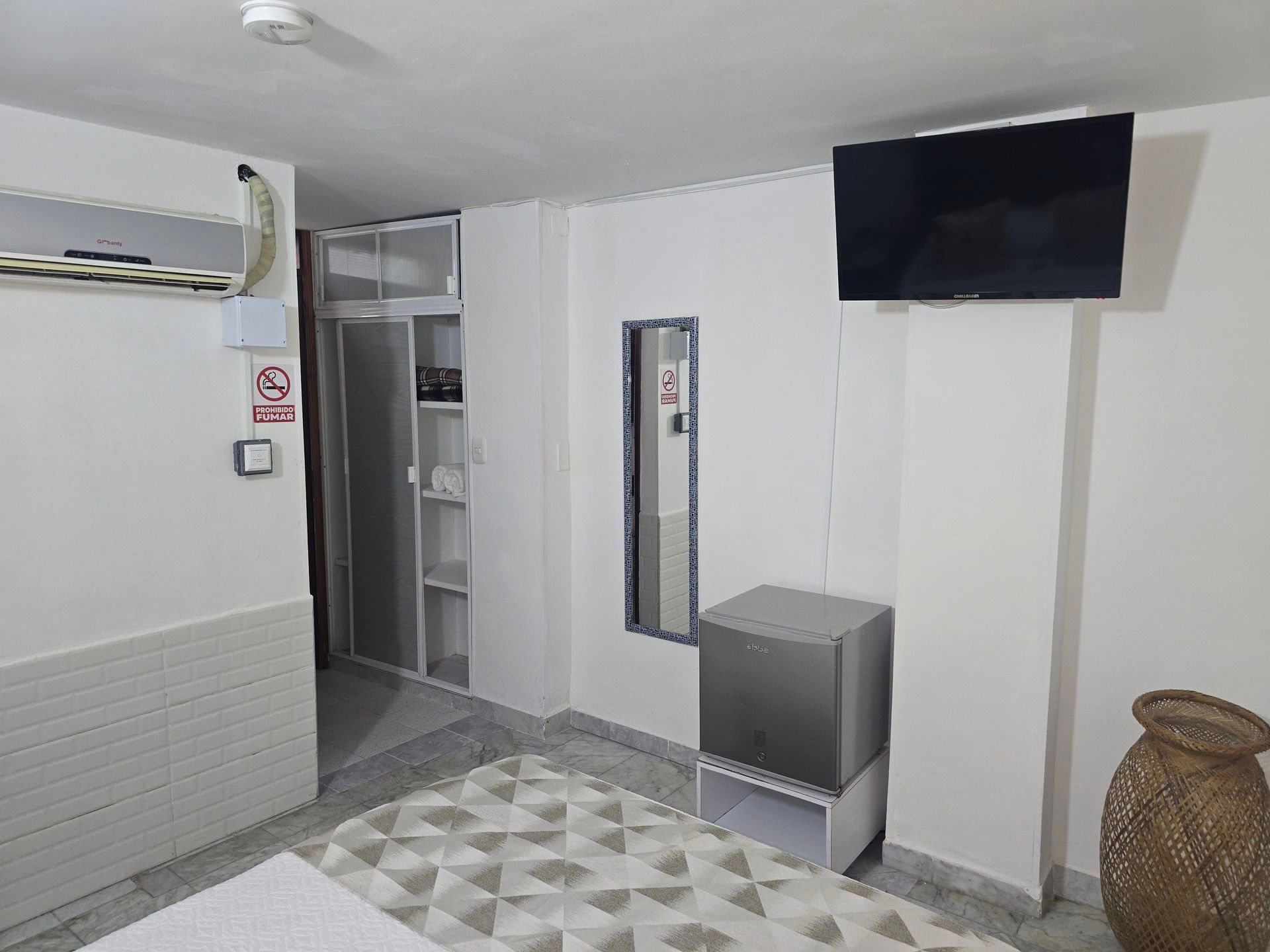 Una habitación de hotel blanca con un pequeño refrigerador