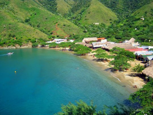Una playa de arena enclavada en una bahía de montaña verde