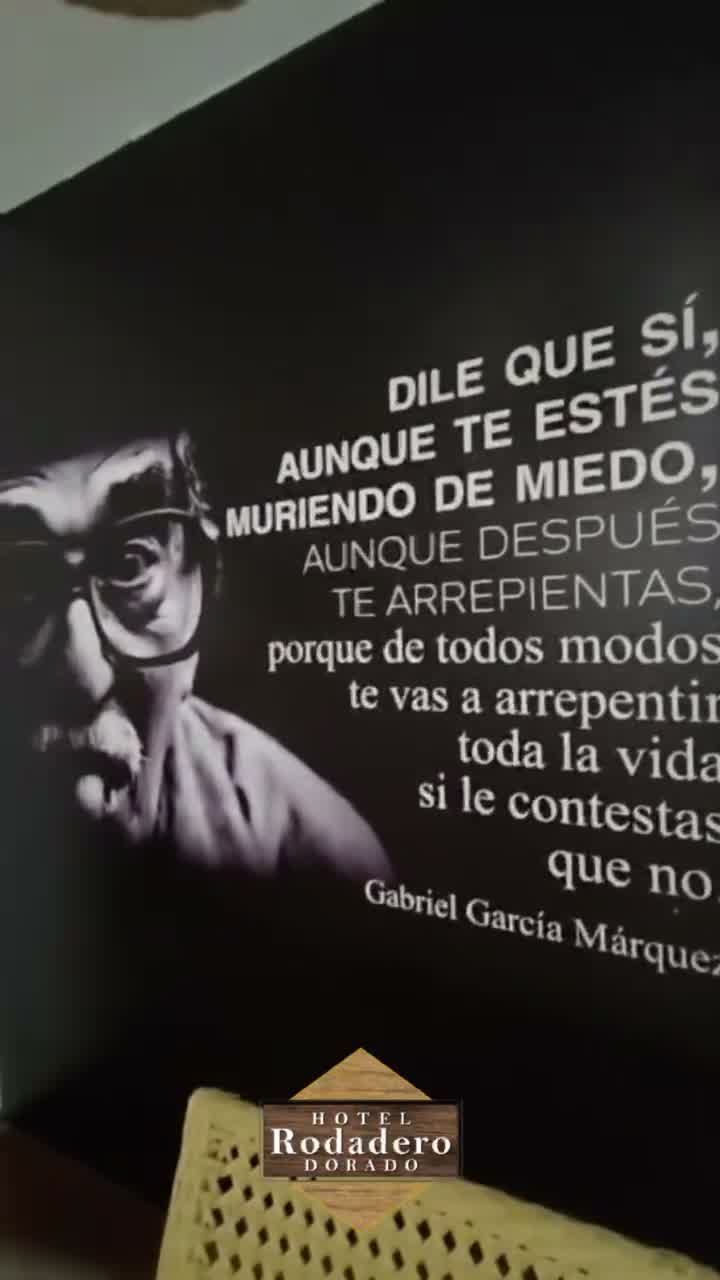 Una cita en español en una pared oscura junto a un retrato en blanco y negro de Gabriel García Márquez.