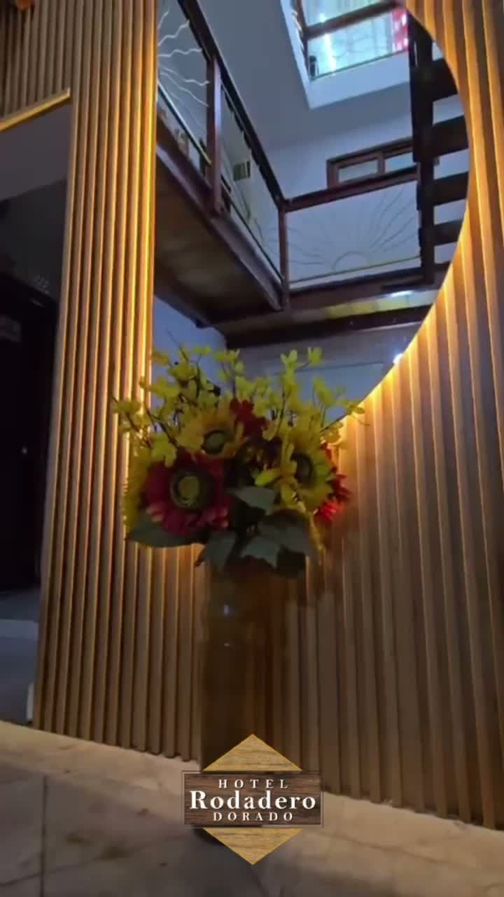Alto atrio interior con balcones de madera y un gran arreglo floral colorido en el centro.
