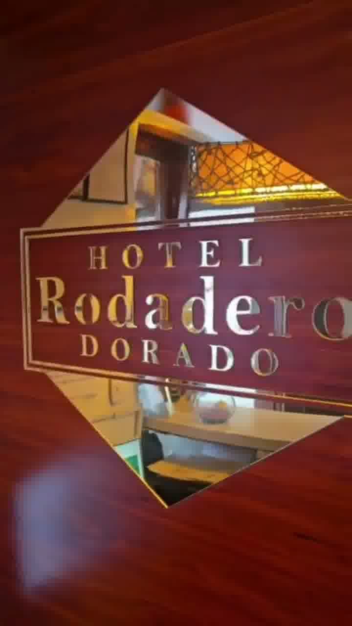 Letrero del Hotel Rodadero Dorado en letras doradas sobre una pared roja con un marco de espejo en forma de diamante.