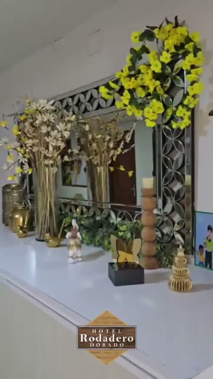 Repisa decorativa con espejo, flores blancas y arreglo floral amarillo sobre un estante blanco.