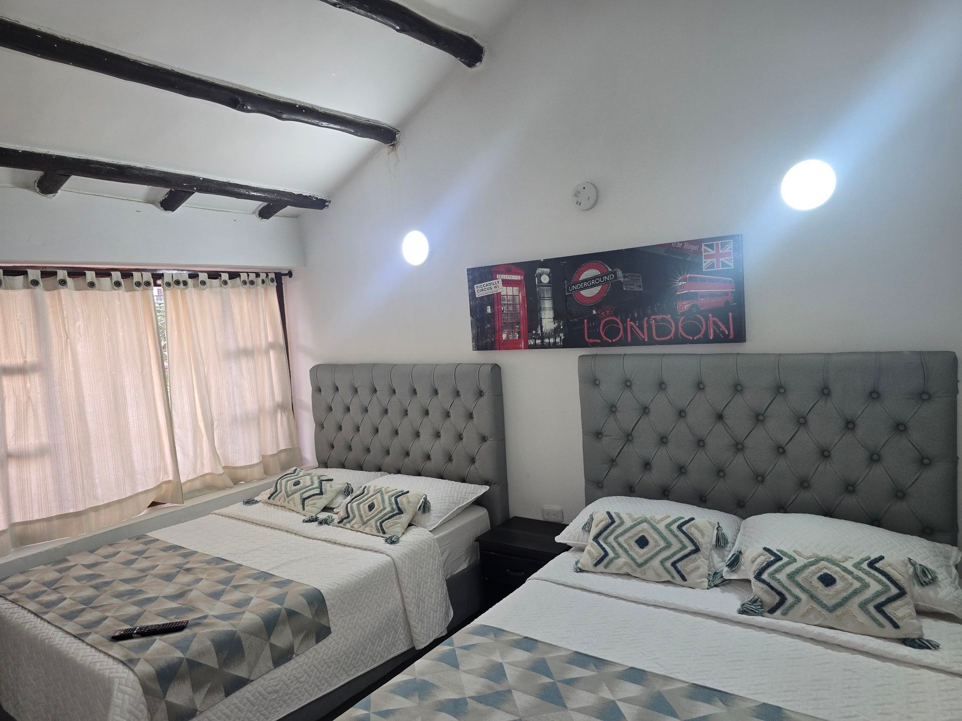 Un dormitorio con dos camas, cabeceros grises acolchados