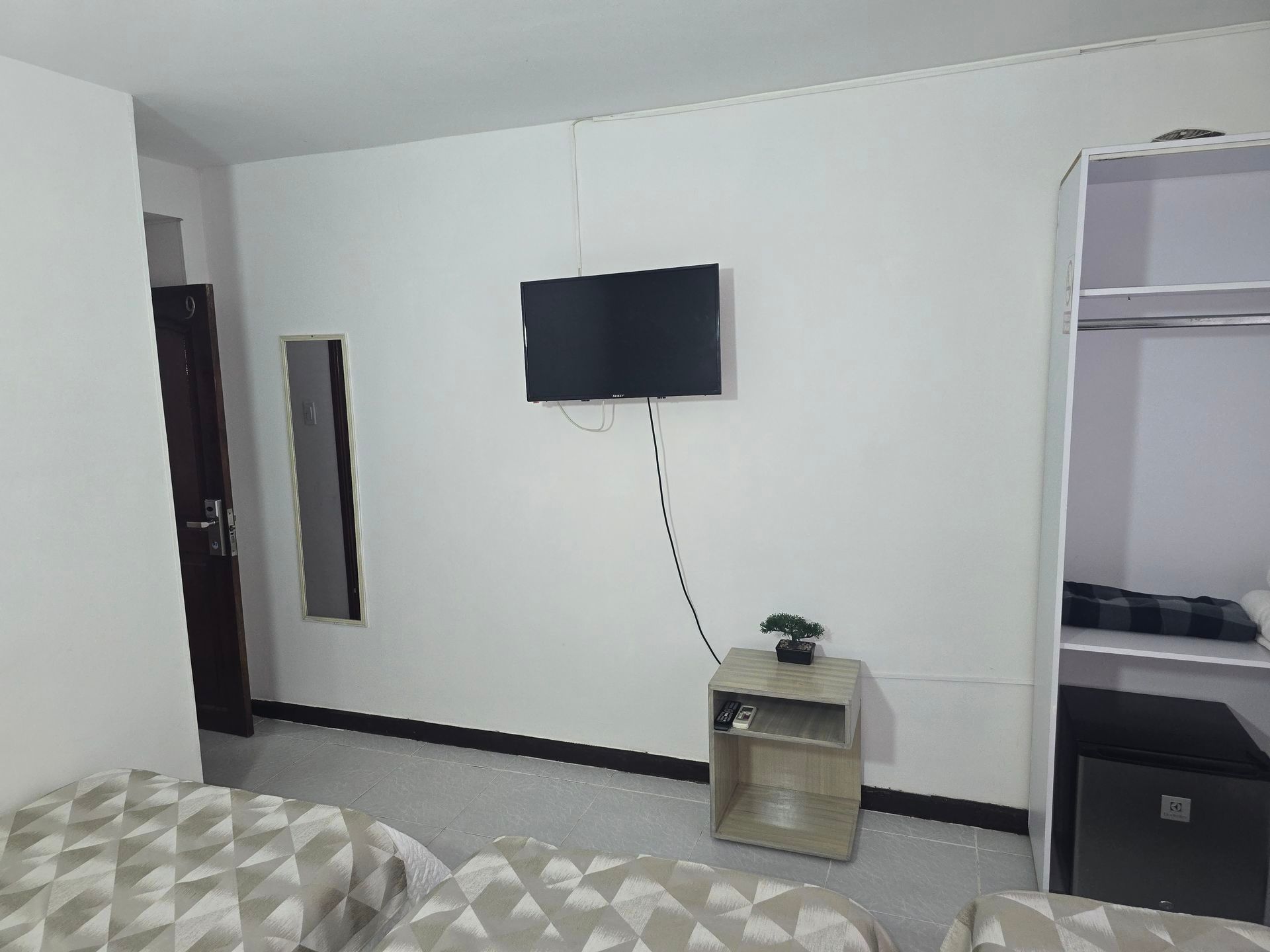 Una habitación de hotel con dos camas, un televisor montado en la pared
