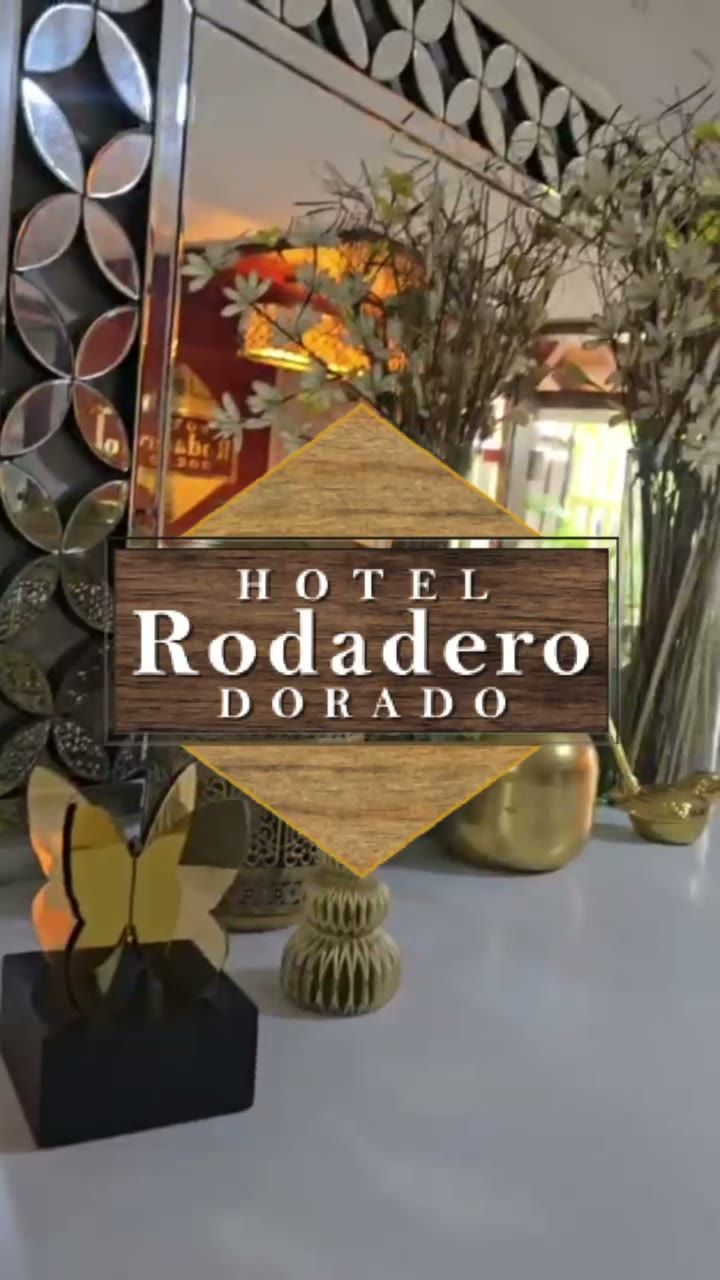 Letrero del Hotel Rodadero Dorado con flores decorativas y jarrones dorados sobre una mesa.
