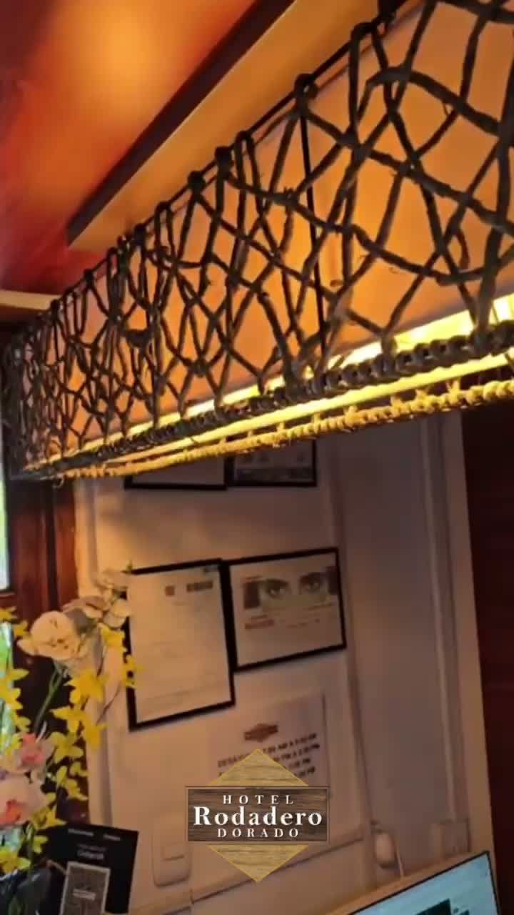 Interior acogedor del restaurante con lámparas colgantes geométricas negras, cuadros enmarcados en la pared y flores sobre una mesa.