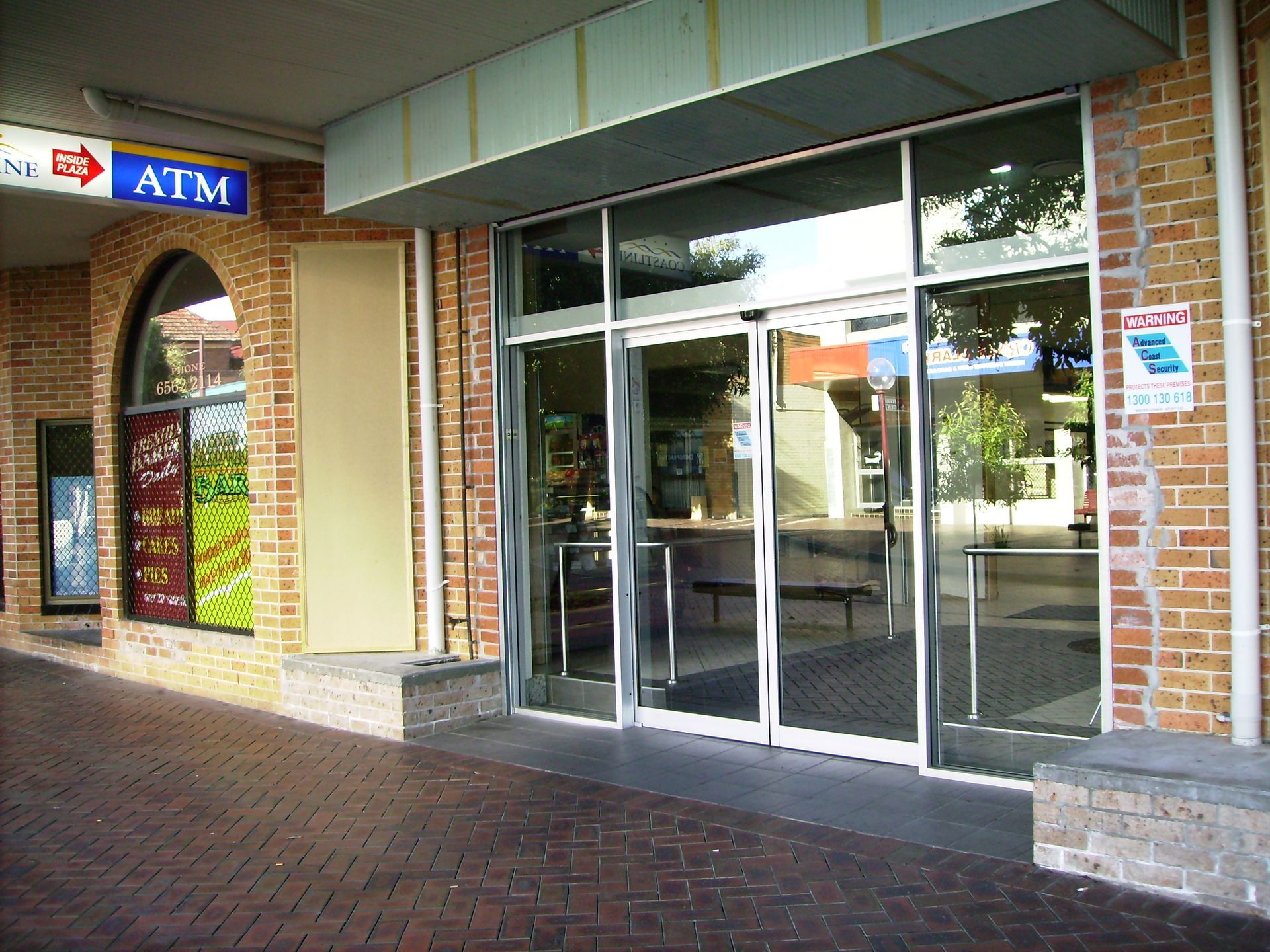 A Brick Building With A Sign That Says Atm On It — Patterson Glass Works in Kempsey, NSW