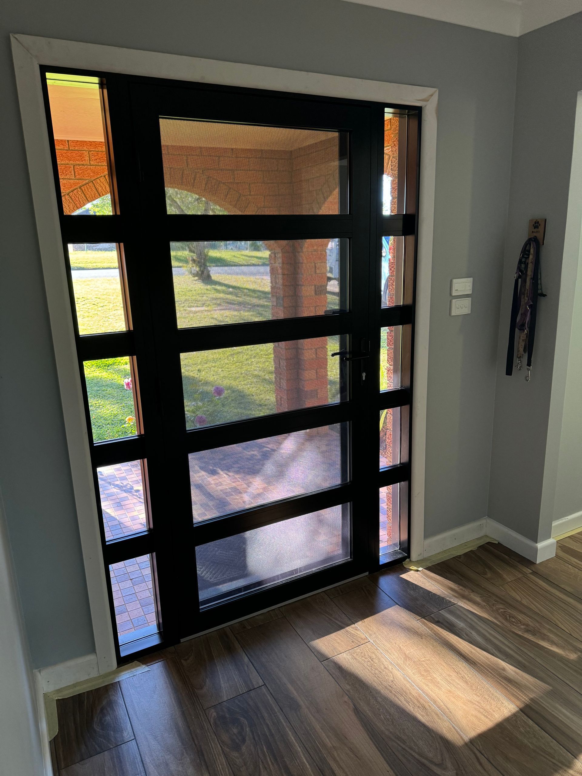 A Black Door With A Lot Of Windows Is In A Room With A Wooden Floor — Patterson Glass Works in Kempsey, NSW