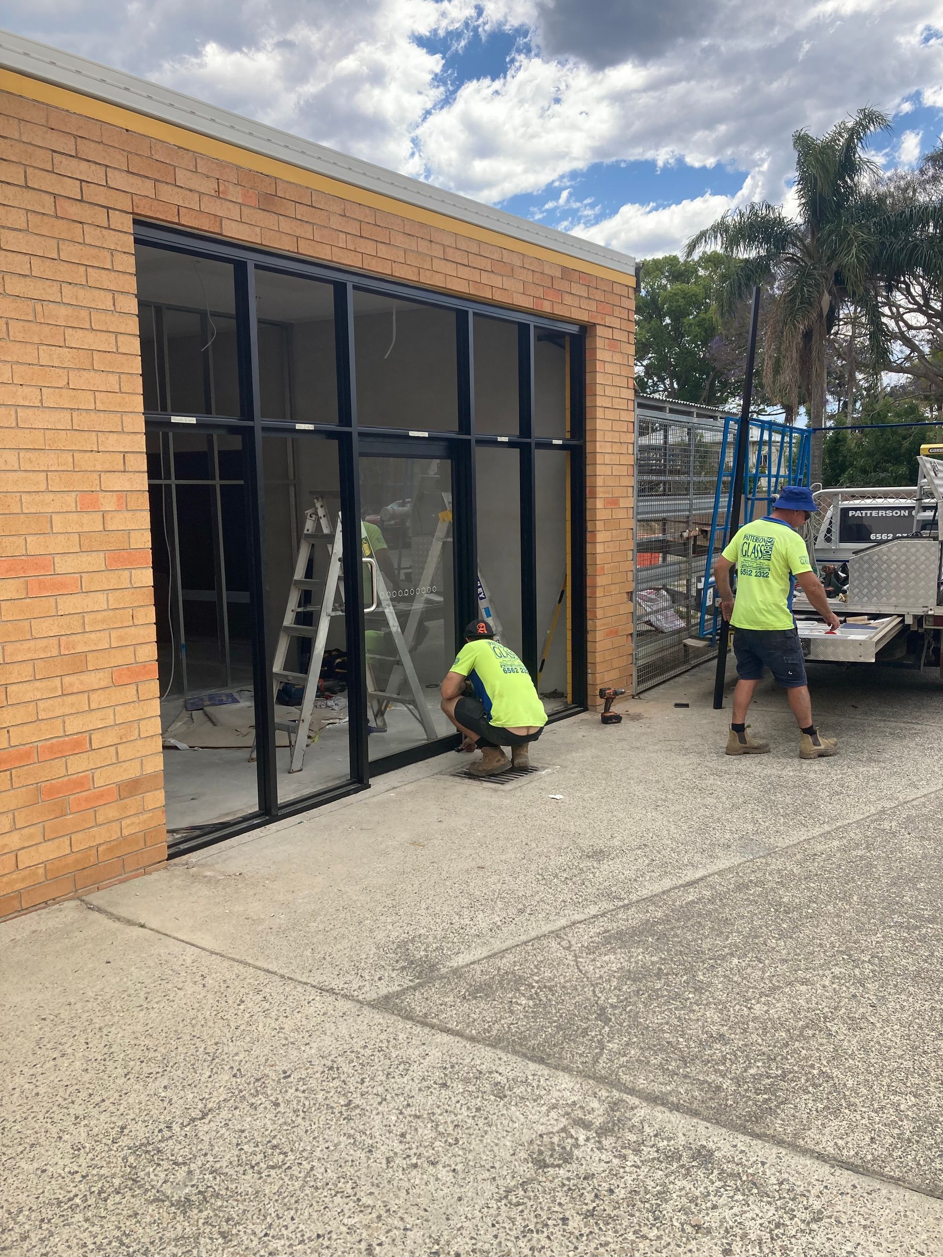 A Couple Of Men Are Working On A Building — Patterson Glass Works in Kempsey, NSW