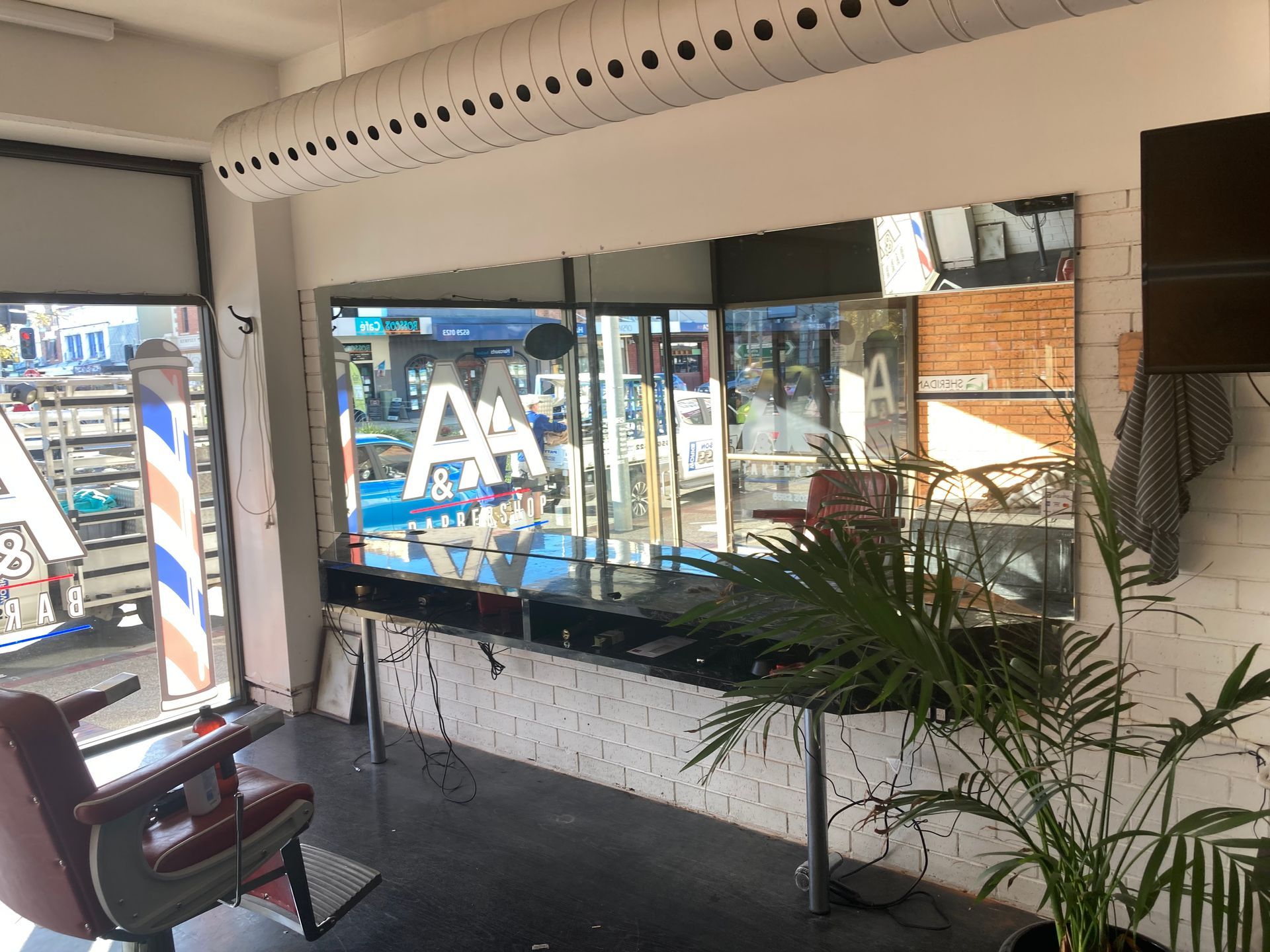 A barber shop with a barber chair and a mirror. — Patterson Glass Works in Kempsey, NSW