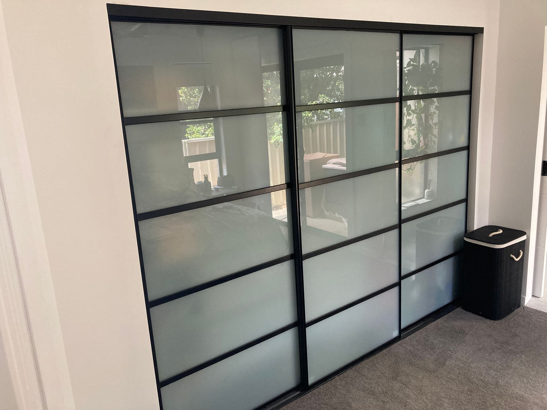 A room with sliding glass doors and a black laundry basket. — Patterson Glass Works in Kempsey, NSW