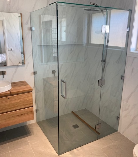 A Bathroom With a Walk in Shower With a Glass Door and a Shower Head — Patterson Glass Works in Kempsey, NSW