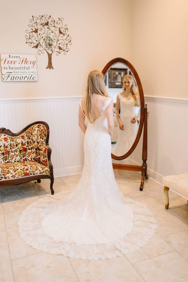 A woman in a wedding dress is standing in front of a mirror.