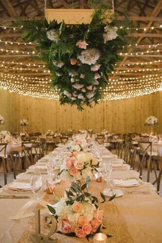 A long table with flowers and lights hanging from the ceiling.
