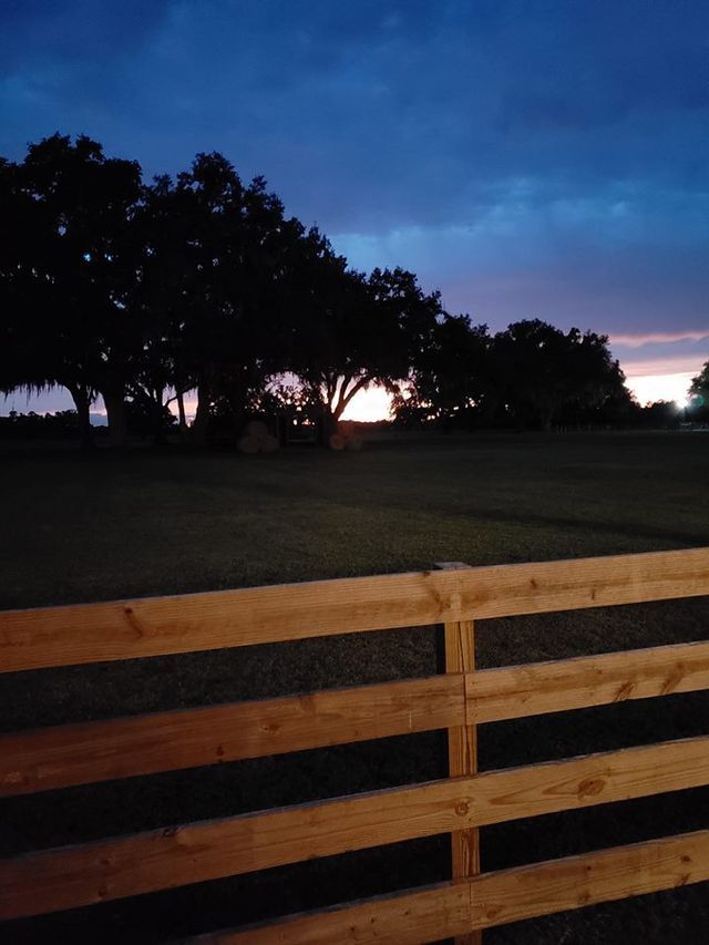 A wooden fence with a sunset in the background