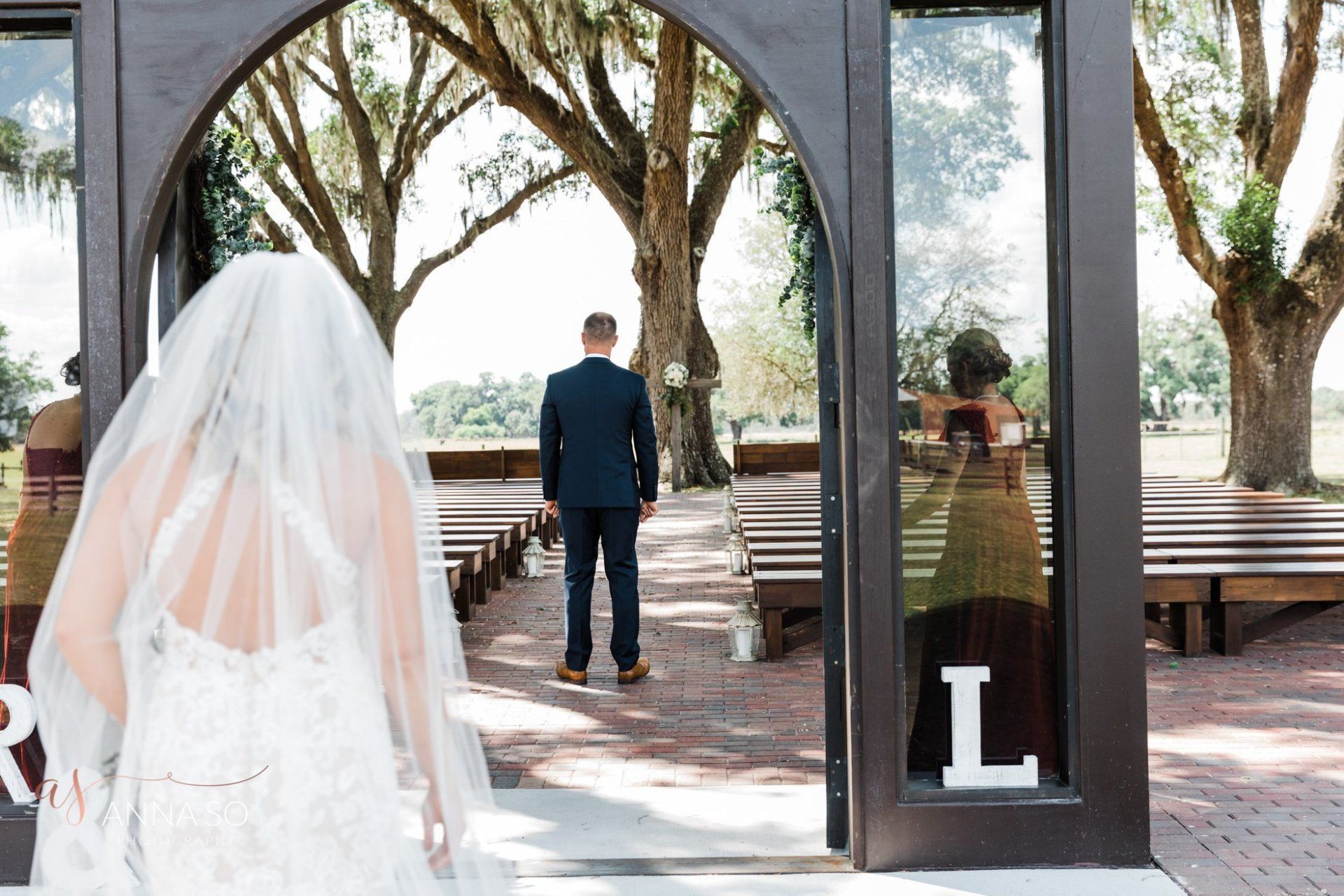 A bride and groom are standing in front of a door with the letter l on it.