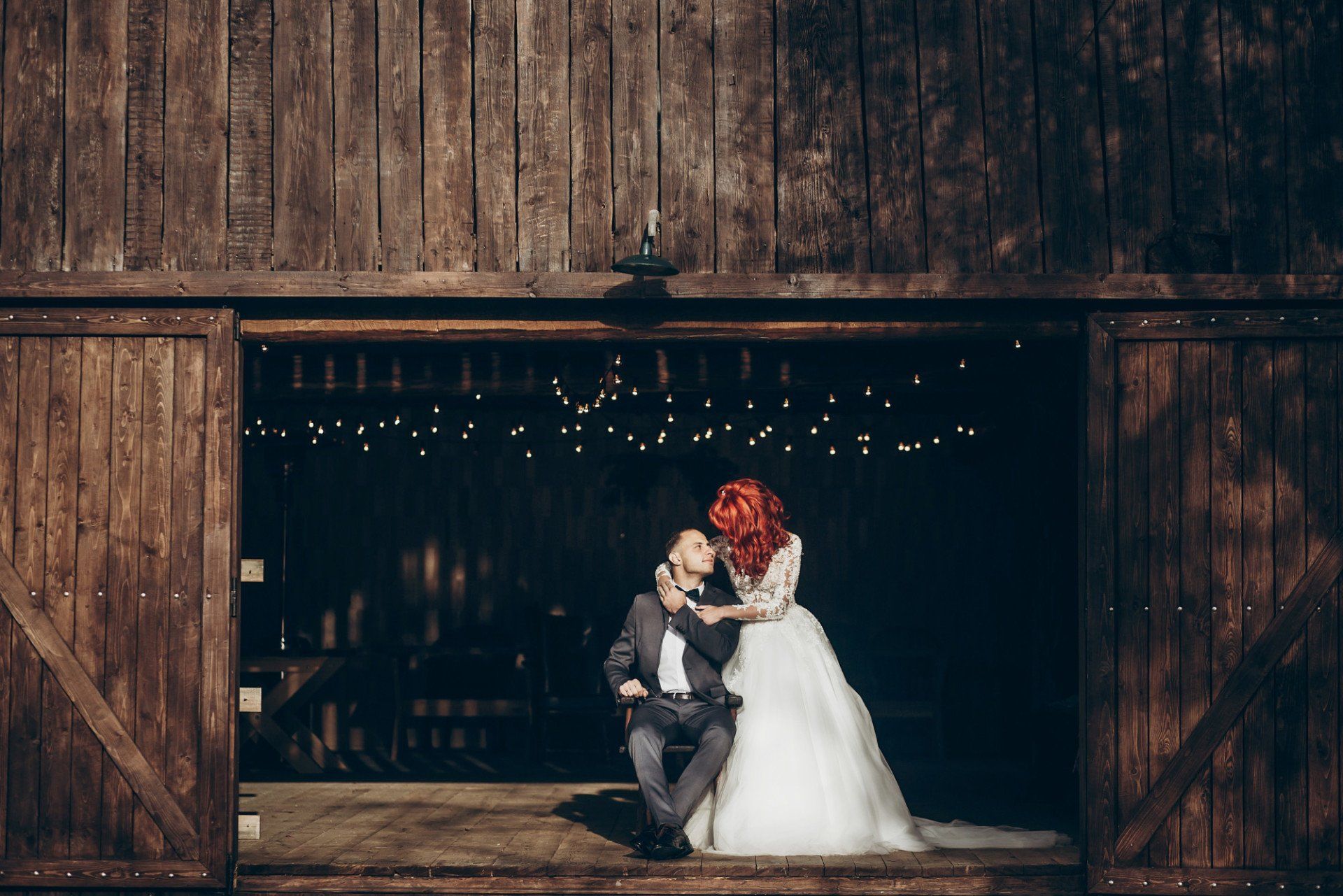 A bride and groom are posing for a picture in front of a wooden barn.
