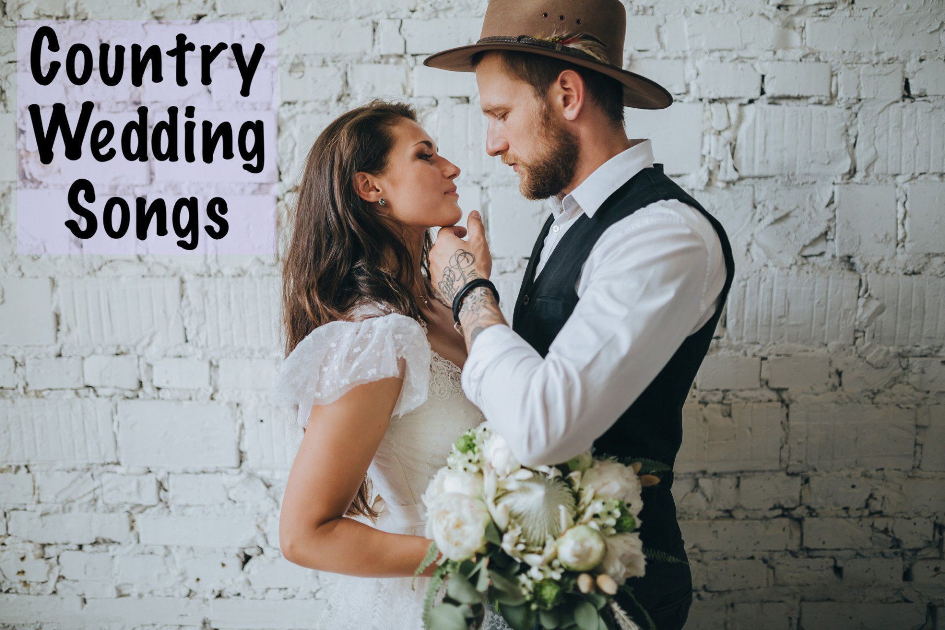 A bride and groom are kissing in front of a white brick wall.