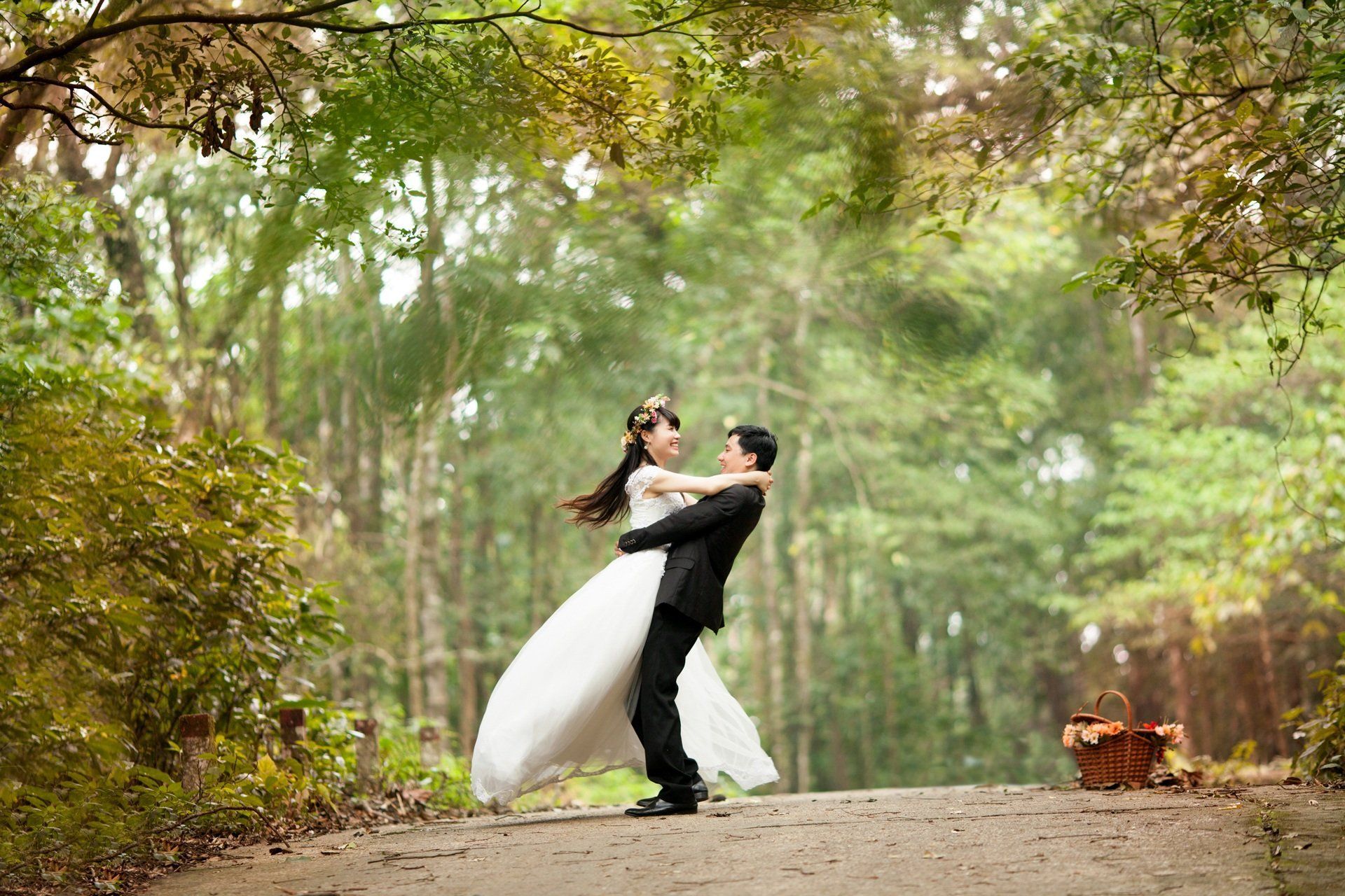 A bride and groom are dancing in the woods.