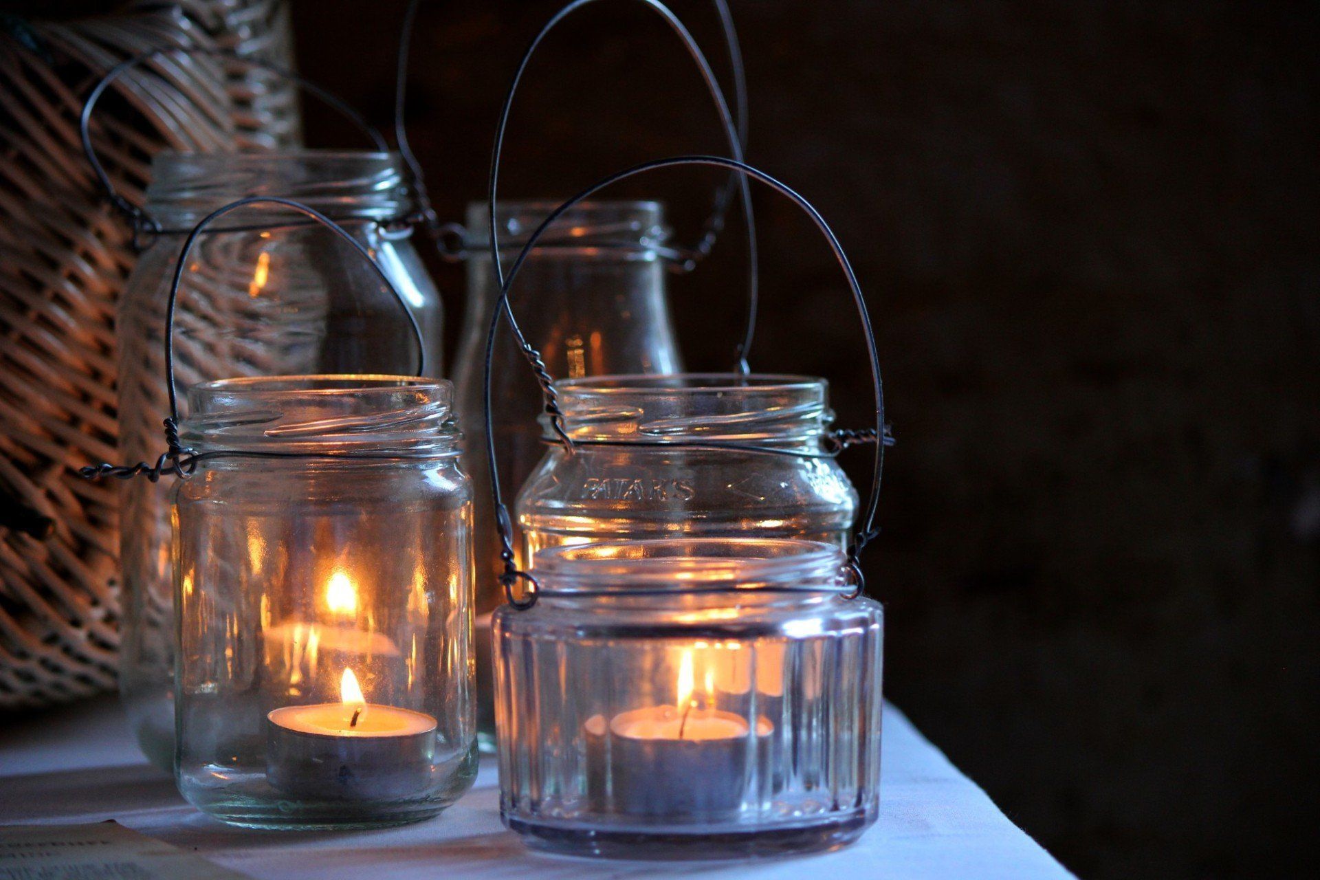 A group of jars with candles inside of them on a table.