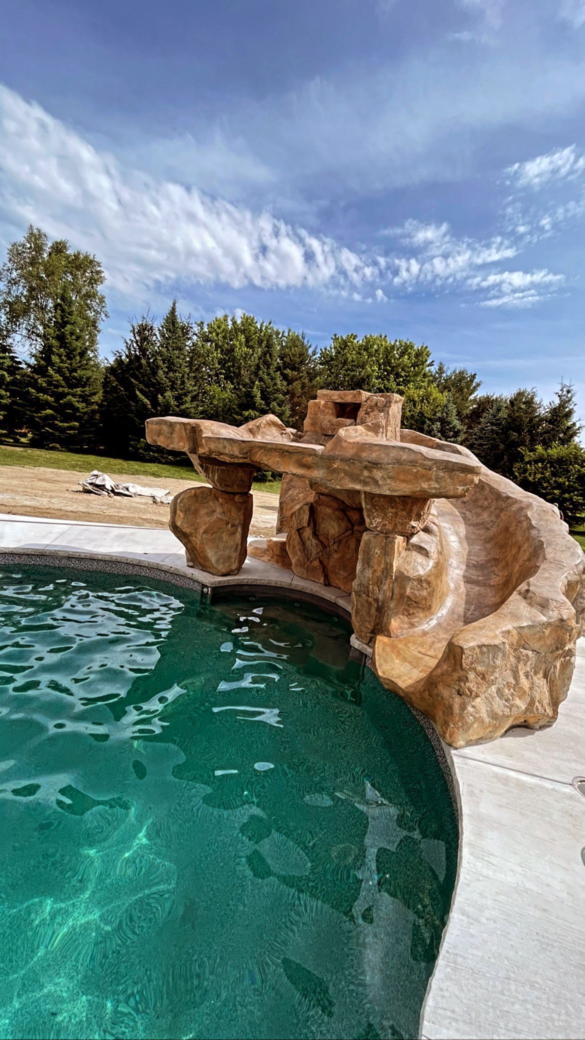 Pool with rock feature under a blue sky, water is turquoise.