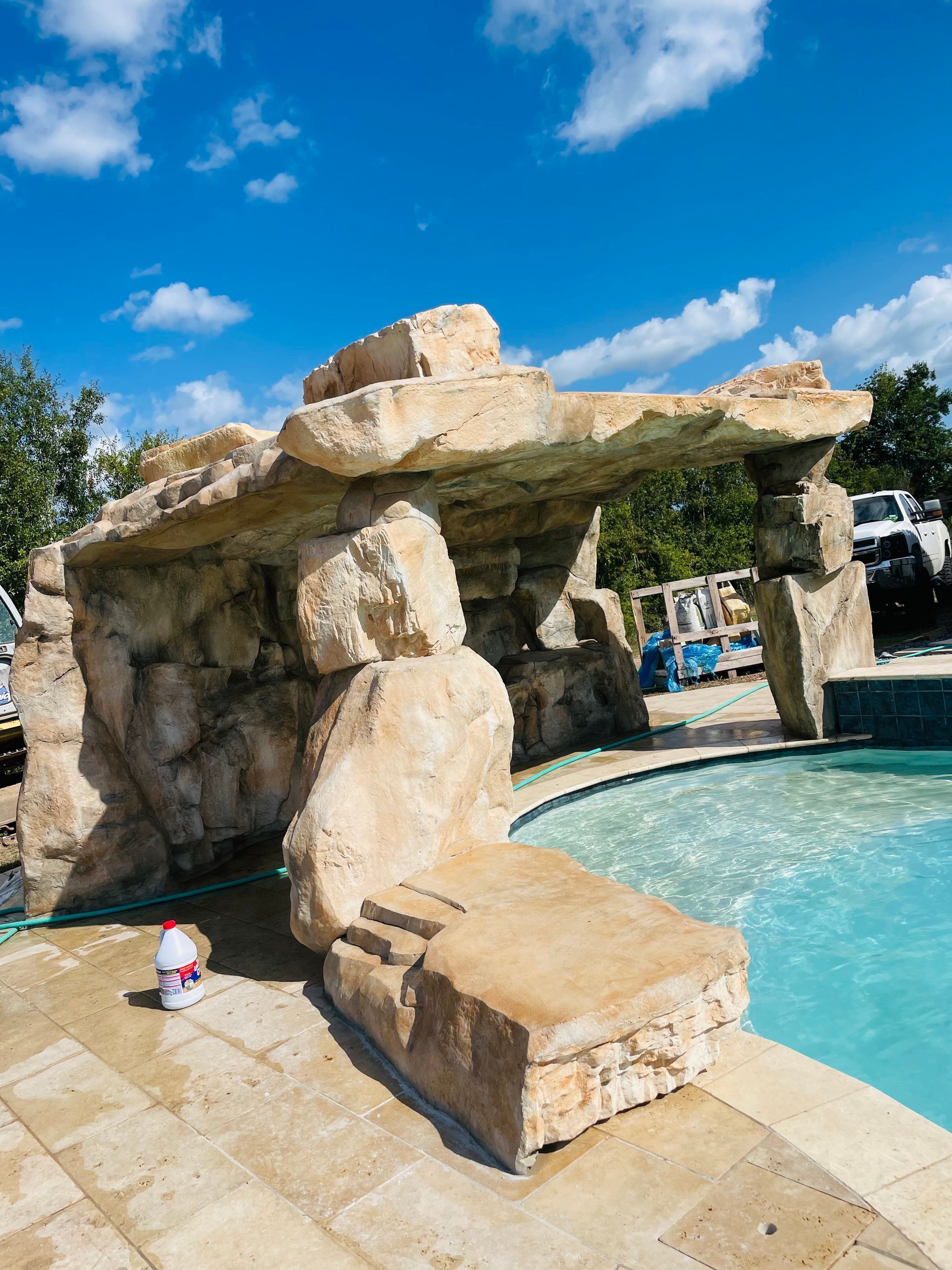 Poolside grotto structure with steps, rock-like texture, under blue sky.