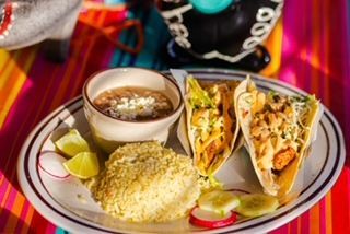 A plate of tacos and a bowl of salsa on a table.