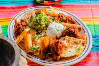 A plate of mexican food is sitting on a colorful table cloth.