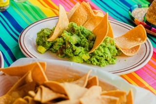 A plate of guacamole and tortilla chips on a table.
