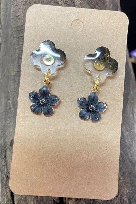 Earrings with light and dark flower charms displayed on a cardboard tag.
