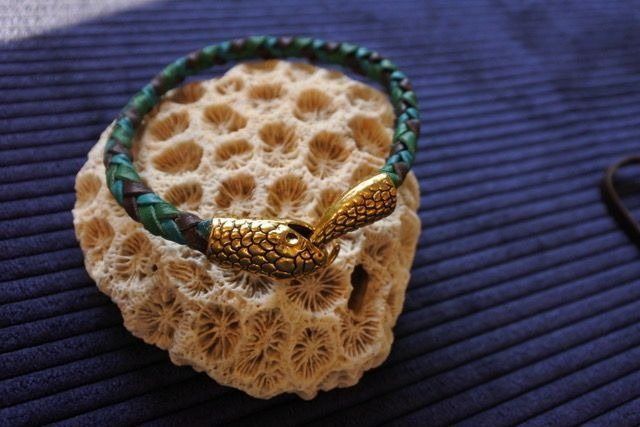 Braided teal and brown leather bracelet with gold clasp on porous tan coral.