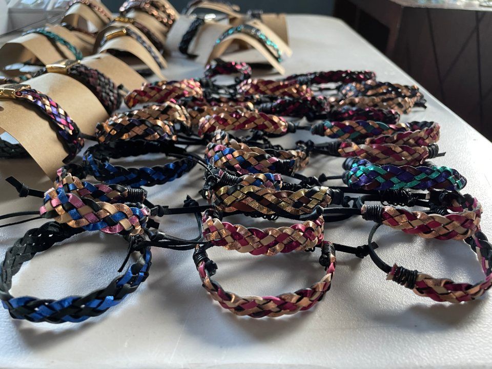 Bracelets with woven metallic details in various colors displayed on a table.