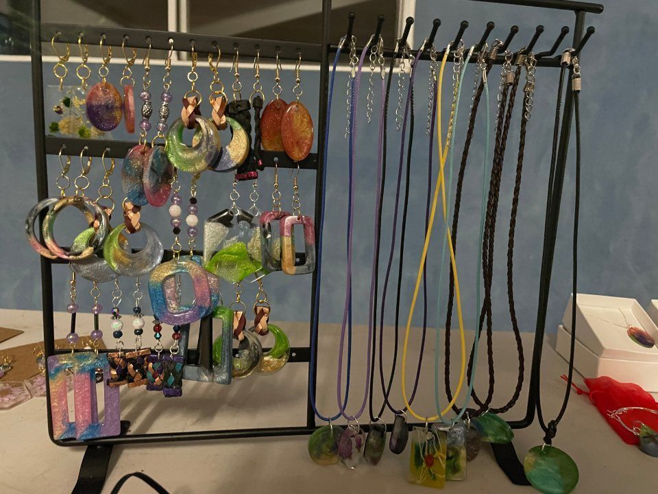 Jewelry display with earrings and necklaces hanging on black metal racks.