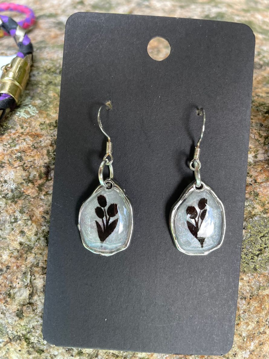 Dangling earrings with woven cylinder charms. Silver hooks, small beads, and colorful, fabric-wrapped cylinders.