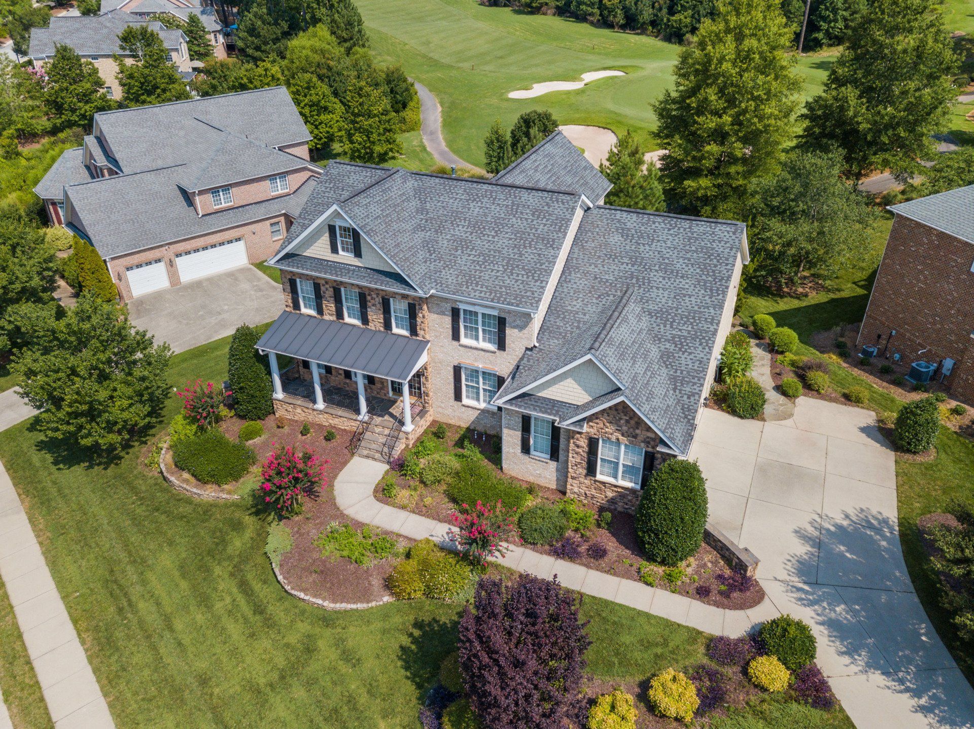 An aerial view of a large house with a golf course in the background.