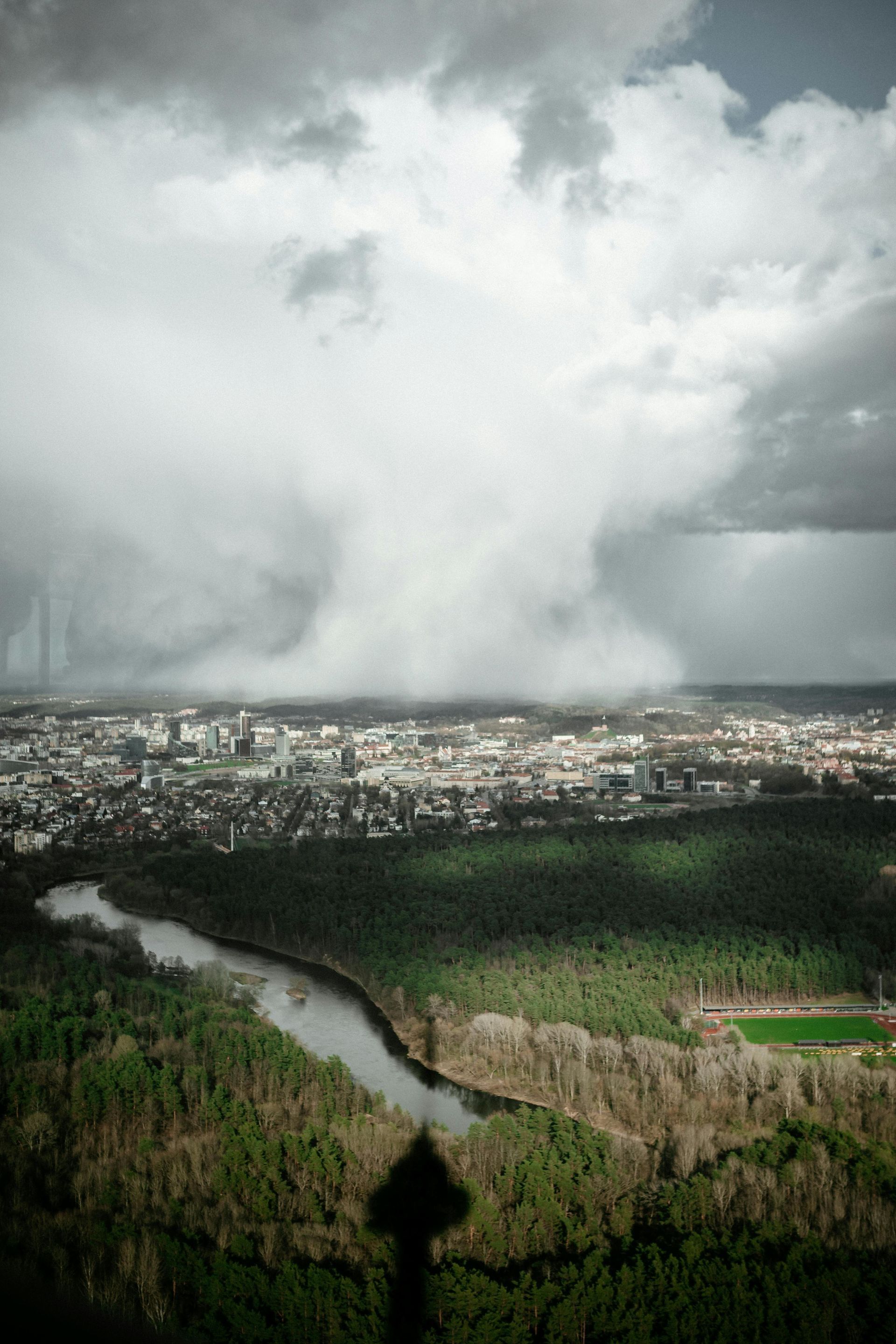An aerial view of a city and a river with a cloudy sky in the background.