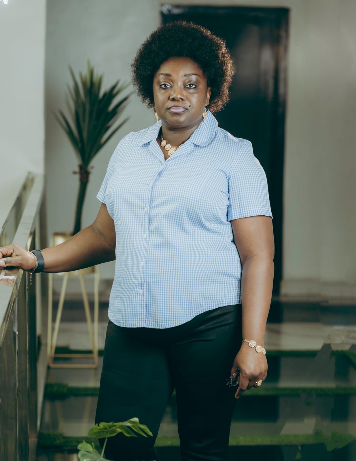 A woman is sitting at a desk with a laptop and a vase of flowers.