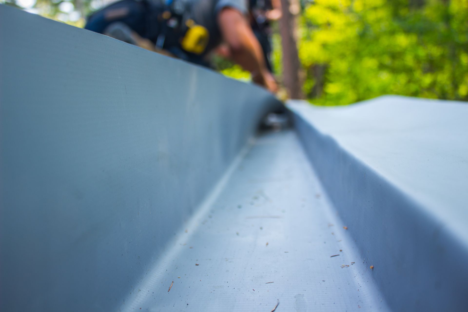A person working on a metal roof, close-up of the gutter.