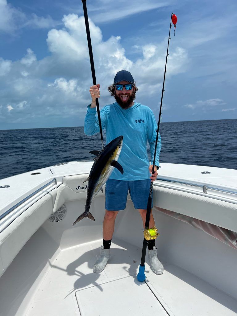 A man is standing on a boat holding a fish