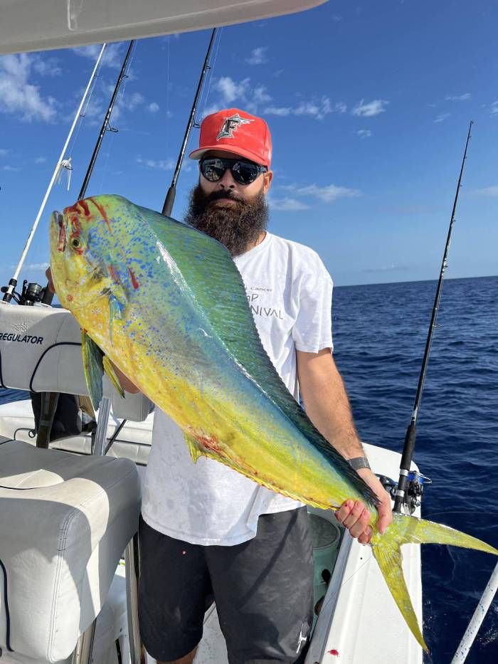 A man is holding a large fish on a boat in the ocean.