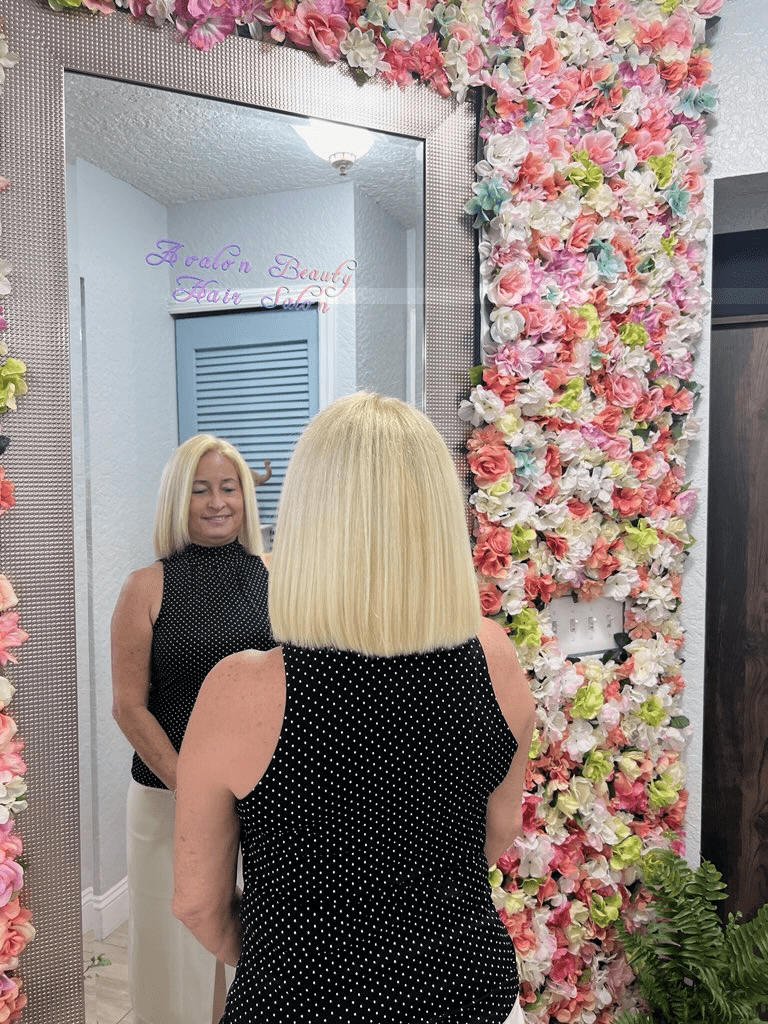 A woman is standing in front of a mirror surrounded by flowers.