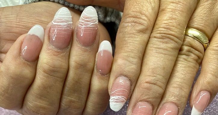 A close up of a woman 's nails with a wedding ring on her finger.