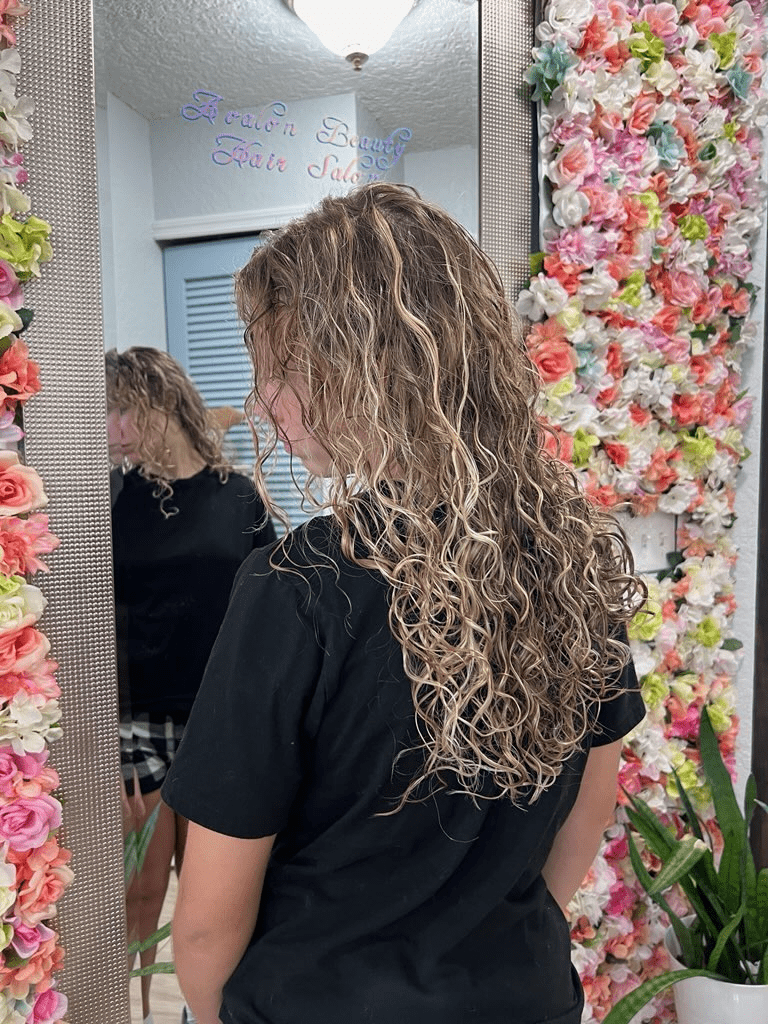 A woman is standing in front of a mirror with flowers on the wall.