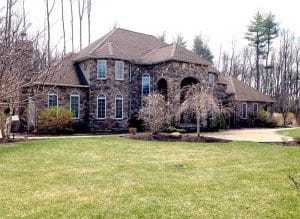 A large stone house with a lush green lawn in front of it.