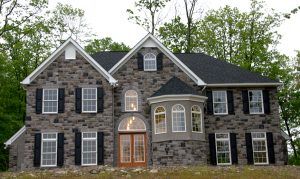A large stone house with black shutters on the windows