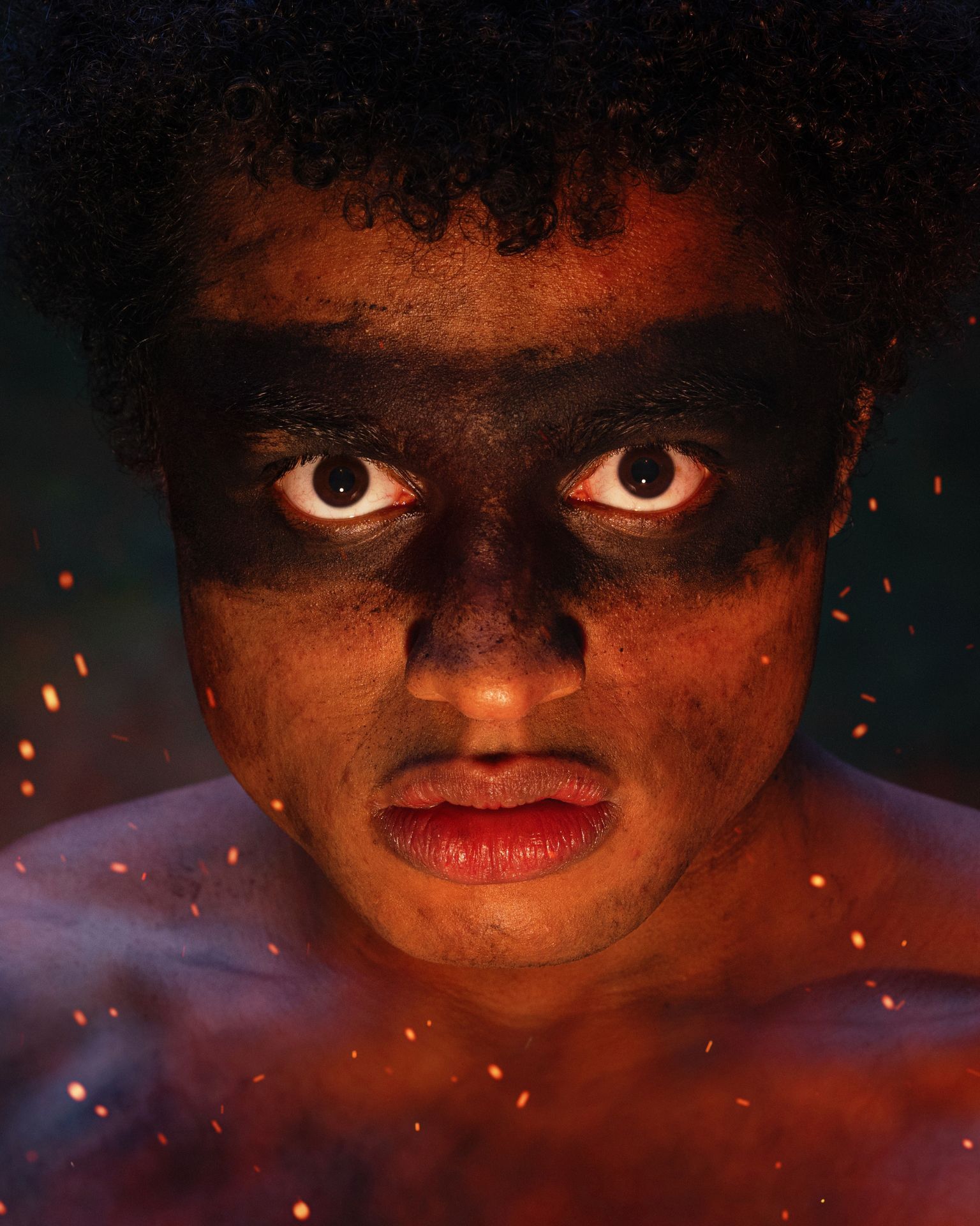 A man with black paint on his face is looking at the camera.