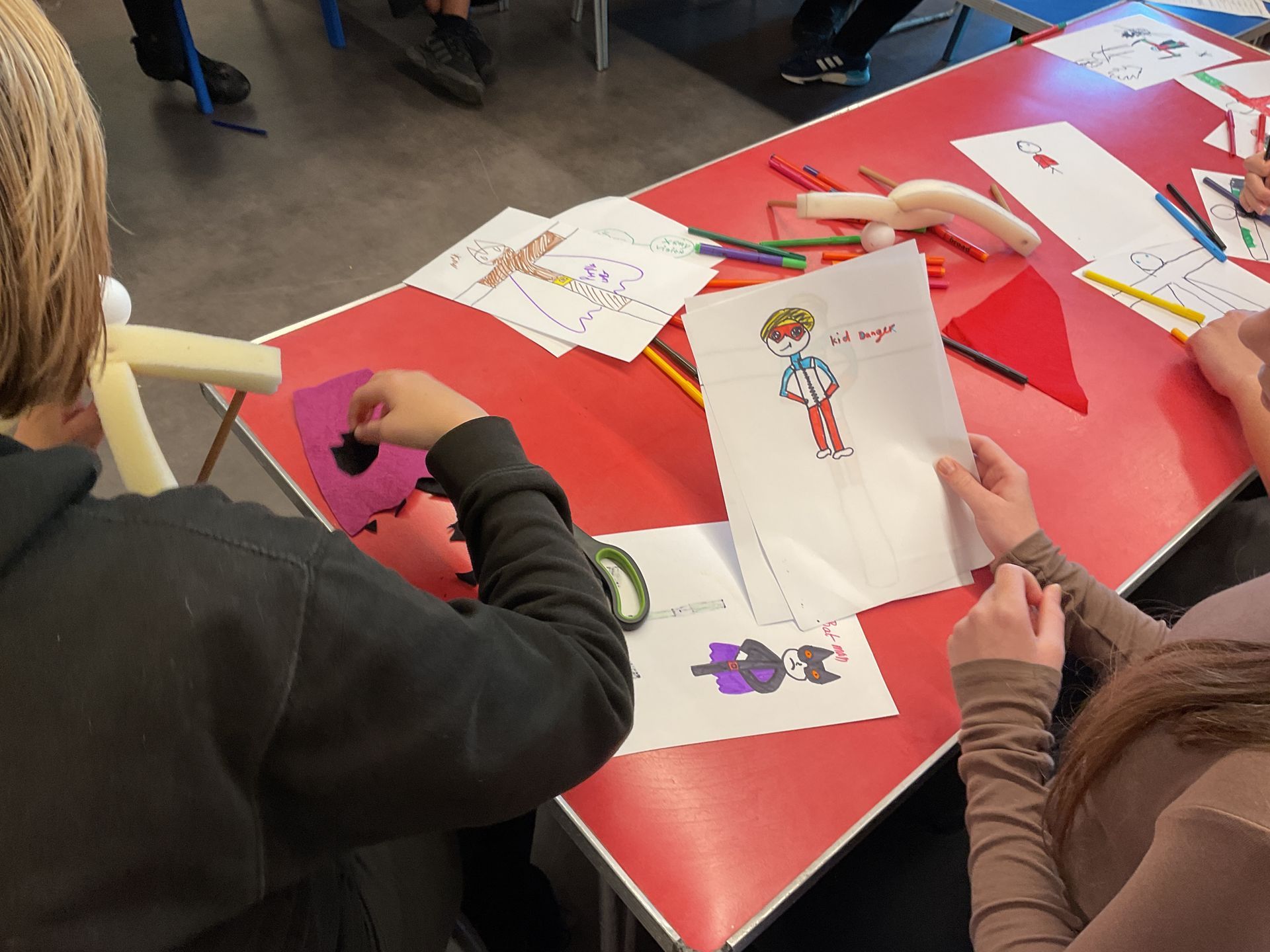 A group of children are sitting at a table with drawings on it