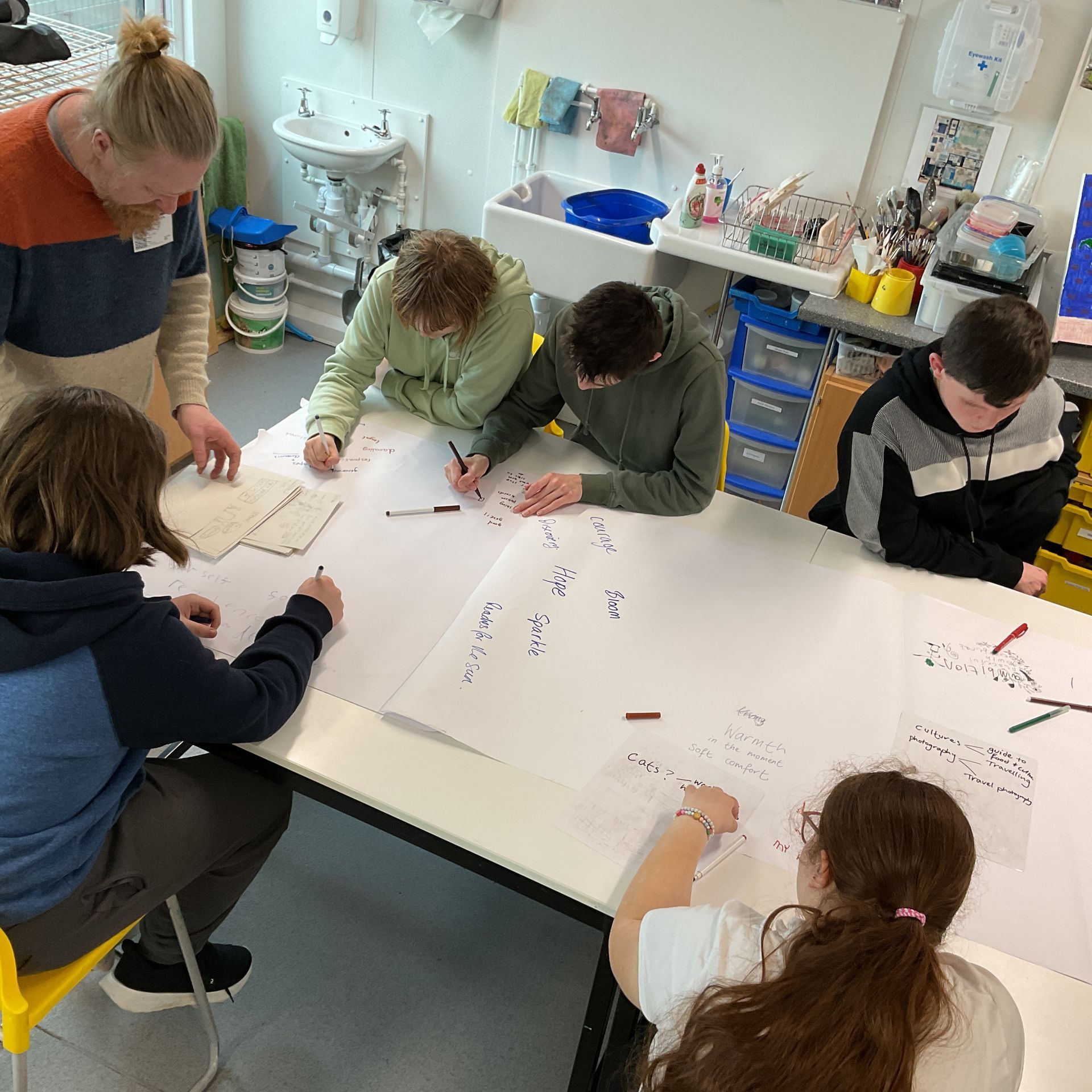 A group of people are sitting around a table writing on paper.